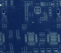 Close-up of a mylar solder paste stencil (the mylar is not stretched flat, making the apertures look distorted).